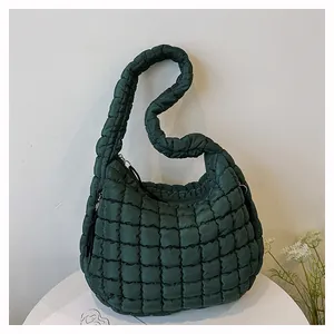 Detailed close-up of dark green quilted shoulder bag with puffy padded nylon texture
