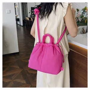 Bright pink quilted puffer tote bag worn by model in a cozy cafe setting