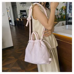 Detail of light pink nylon puffy bag featuring drawstrings and knotted handle design