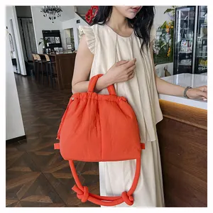 Detail of orange quilted puffer bag with drawstring closure and knotted strap