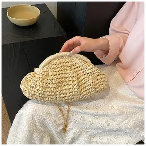 Détail de la pochette nuage en paille beige avec texture fine et chaîne en métal doré