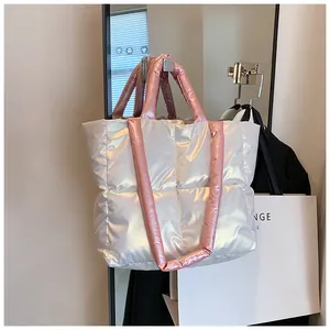 Detail of silver puffer tote bag featuring pink quilted straps and glossy padded texture