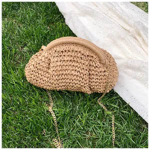 Détail d'un sac nuage en paille tressée avec chaîne métallique sur fond d'herbe