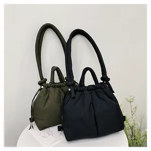 Close-up of quilted nylon down tote bags in dark green and black with drawstring detail