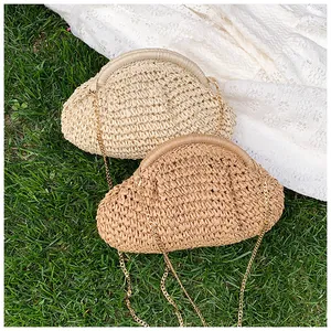 Détail de sacs pochettes en paille tressée avec bandoulière dorée pour vacances à la mer