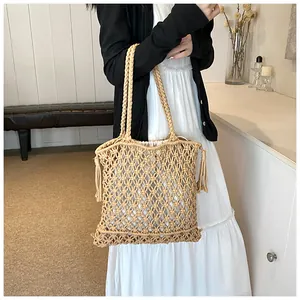 Close-up of bohemian hollow weave pattern and tassel detail on the beige crochet bag