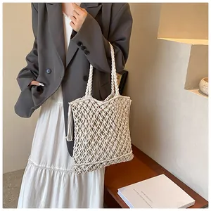 Detailed close-up of bohemian woven net tote bag featuring tassel charm and diamond knit