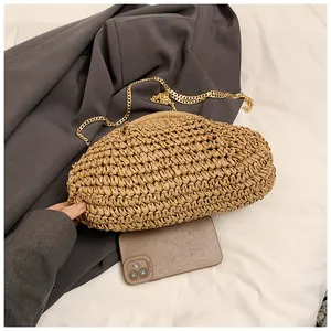 Détail du sac nuage en paille tressée avec une fine chaîne dorée sur fond épuré