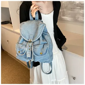 Detalle de mochila de mezclilla azul claro con hebillas metálicas vintage y textura en modelo