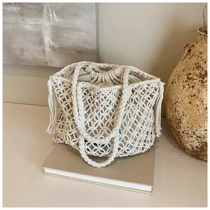 Detail of white woven mesh beach bag featuring decorative tassels and drawstring liner