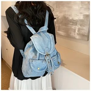 Vista de detalle de una mochila vaquera azul claro con dos bolsillos en modelo