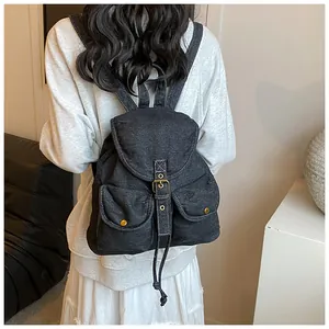Vista trasera de una mochila vintage de mezclilla gris oscuro con costuras blancas en modelo