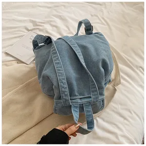 Detalle de mochila de mezclilla azul con hebillas metálicas en fondo de tela