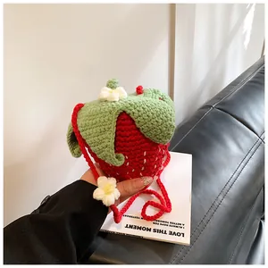Detail of strawberry crochet crossbody bag showing red knit texture and green leaf accents