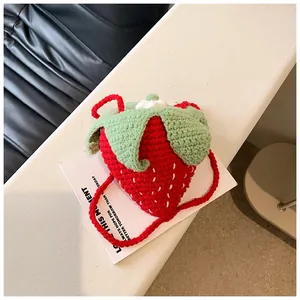 Close-up of handmade crochet strawberry bag with green leaves and white floral detail