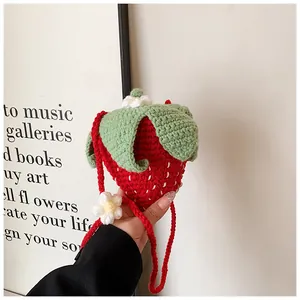 Close-up of handmade crochet strawberry bag featuring knit textures and floral details
