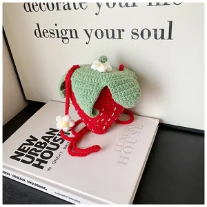 Close-up of handmade crochet strawberry bag with green leaf lid and white flower detail
