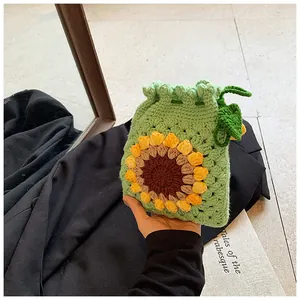 Detailed view of hand-crocheted green drawstring bag with yellow sunflower accent
