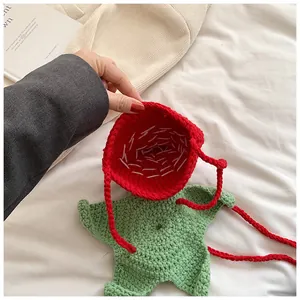 Close-up of handmade crochet strawberry bag featuring red knit texture and green leaf detail