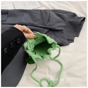 Detail of green knitted bucket bag showing drawstring closure and woven texture
