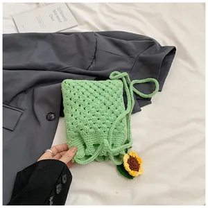 Detail of light green crochet phone bag featuring a handmade sunflower and woven strap
