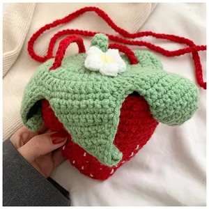 Macro detail of hand-knitted strawberry shoulder bag showing soft yarn texture and stitches