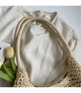 Detailed view of the hollow mesh weave and long rounded handles on a straw tote bag