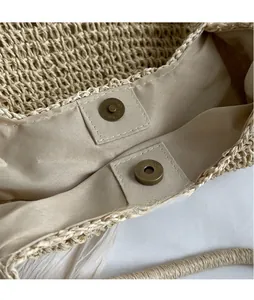 Close-up of vintage bronze magnetic buckle and interior lining on straw tote bag