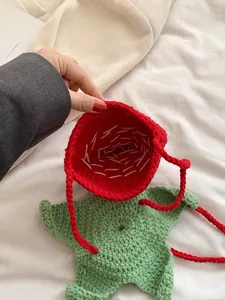 Handmade strawberry crochet bag with red cotton yarn and green leaf detail strap