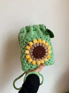 Handmade knitted sunflower drawstring bucket bag in light green with woven shoulder strap