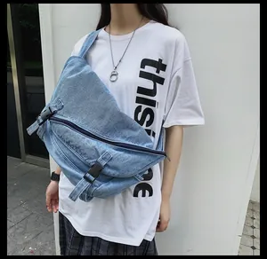 Dettaglio della borsa a tracolla in denim blu chiaro con fibbia nera e cinturino largo