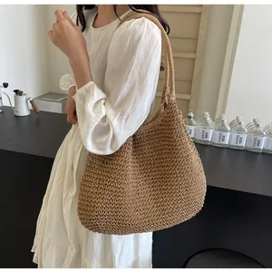 Detailed texture of a brown woven straw tote bag held by a model in a minimalist setting