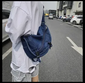 Dettaglio della borsa a tracolla in denim blu con cerniere metalliche e cinghie a fibbia