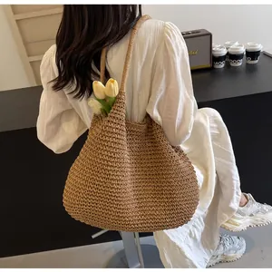 Detailed close-up of woven texture and strap on a large khaki straw beach tote bag