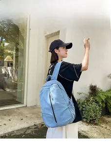 Lichtblauwe gewassen denim rugzak met verticale rits gedragen door een model van 165 cm