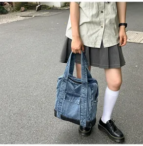 Detail of vintage denim tote bag showing washed fabric texture and front zipper pocket