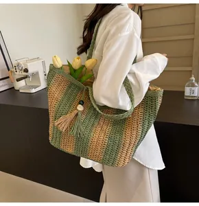 Dettaglio borsa tote in paglia a righe con nappina di perline e tracolla intrecciata