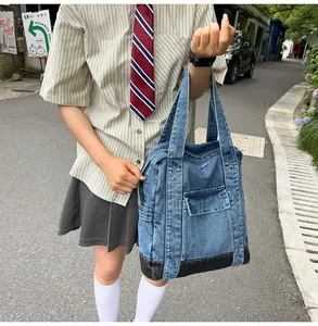 Detail view of denim tote bag with cargo pockets and reinforced black base in outdoor setting