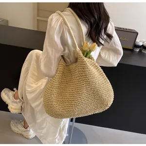 Detail of a large beige straw woven tote bag with thick rope handles for summer beach use