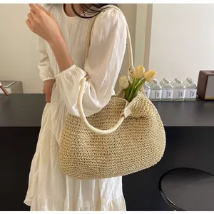 Detailed close-up of a large beige straw woven tote bag worn with a white dress
