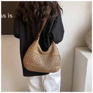 Detail of hand-woven straw bag featuring large mesh hollow design and brown leather strap