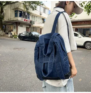 Detail of dark blue washed denim backpack with white stitching and vintage workwear style
