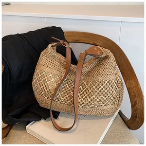Detailed view of beige woven straw tote bag with intricate mesh patterns and leather strap