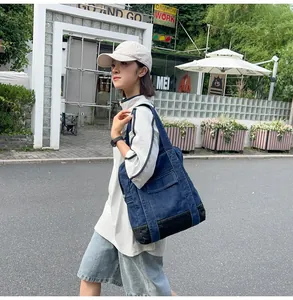 Detail of a large denim tote bag with black base, shown in an urban street setting