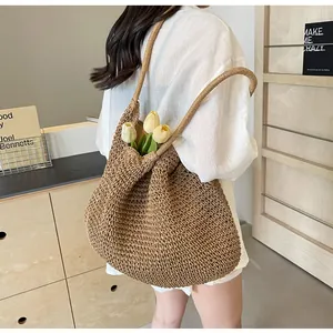 Detailed close-up of brown woven straw tote bag with long straps on model back