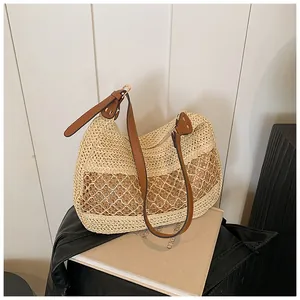 Detail of hollow woven straw tote bag with brown leather strap and gold buckle