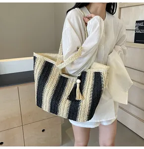 Dettaglio della grande borsa tote in paglia a righe nere con tracolla intrecciata