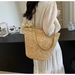 French style straw tote bag with natural weave texture and long shoulder strap in a cafe