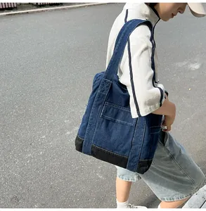Detail of dark blue denim tote bag with yellow stitching and durable black base panel