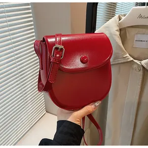 Nahaufnahme einer roten Satteltasche aus Leder mit verstellbarem Gurt und Metallschnalle
